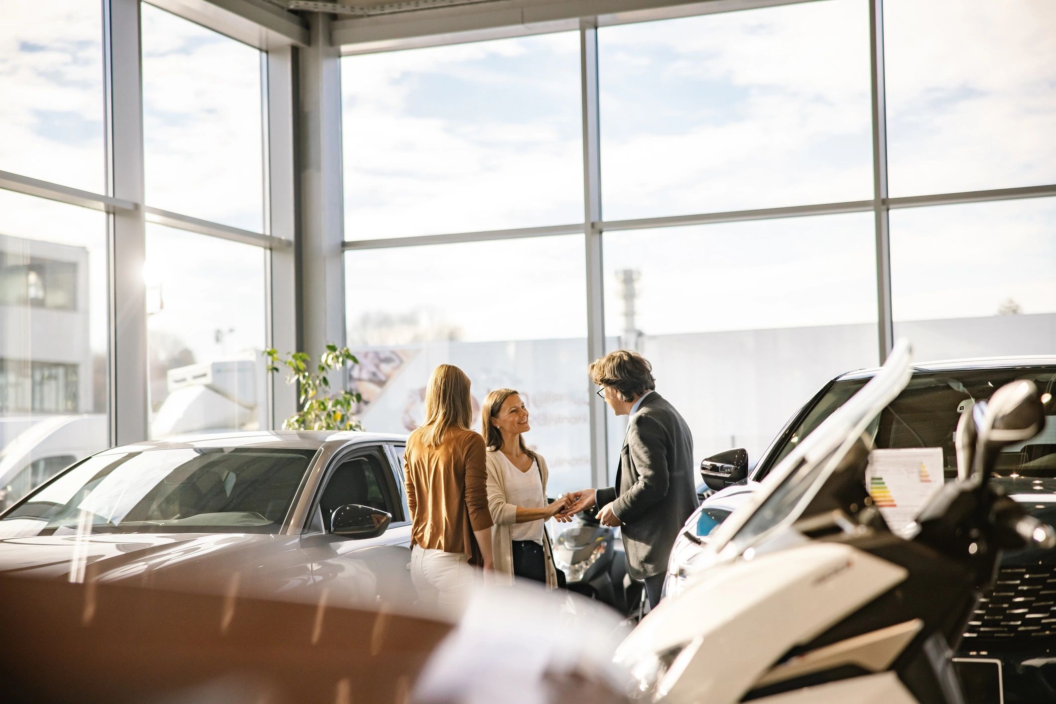 Salesperson handing keys to a customer at a car dealership