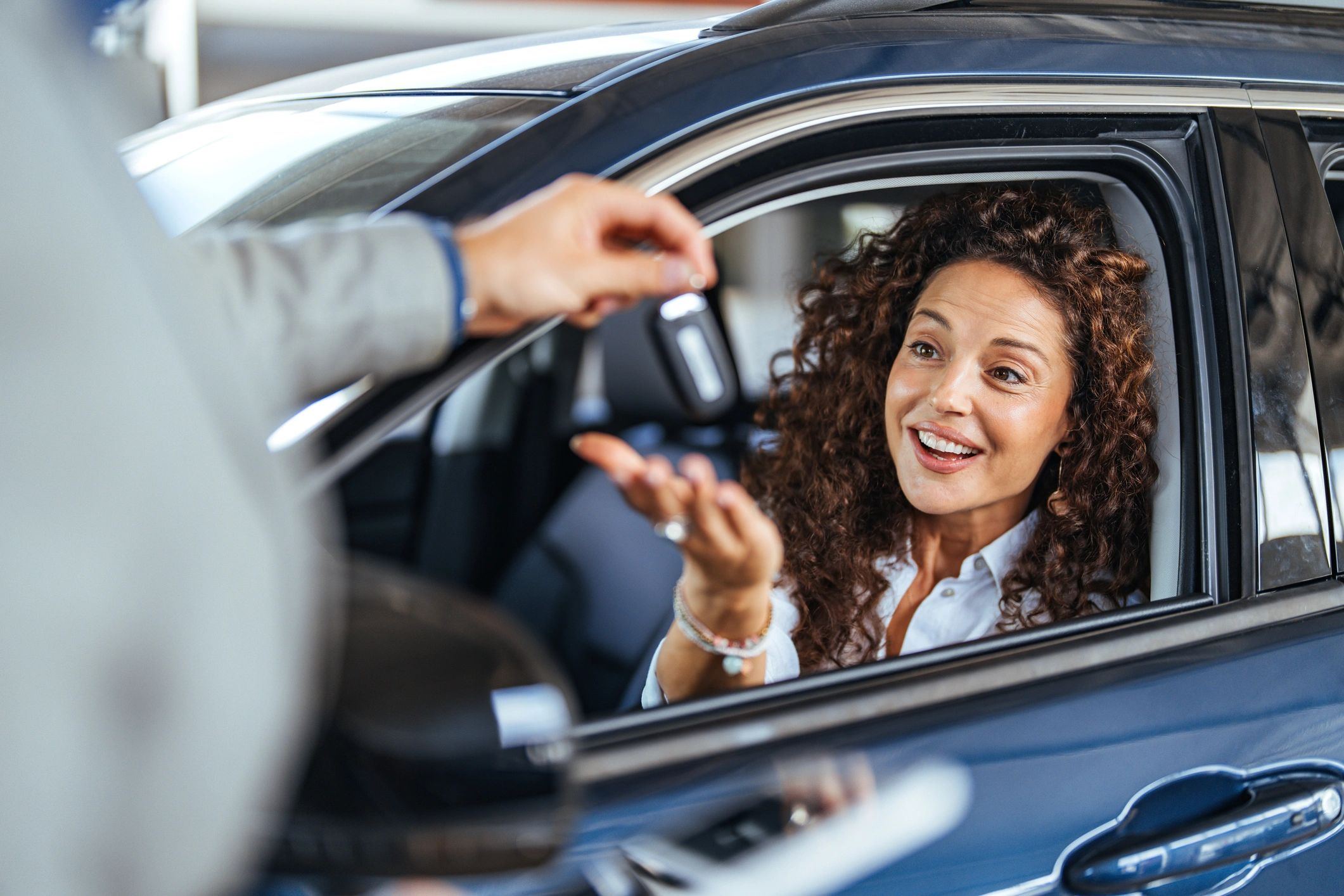Customer receiving car keys inside a vehicle at a dealership